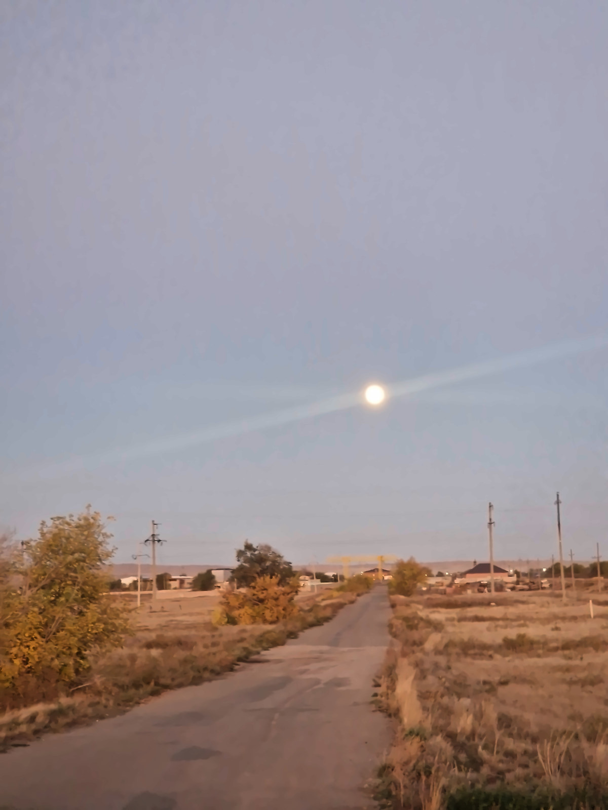 A full moon over a dirt road at dusk