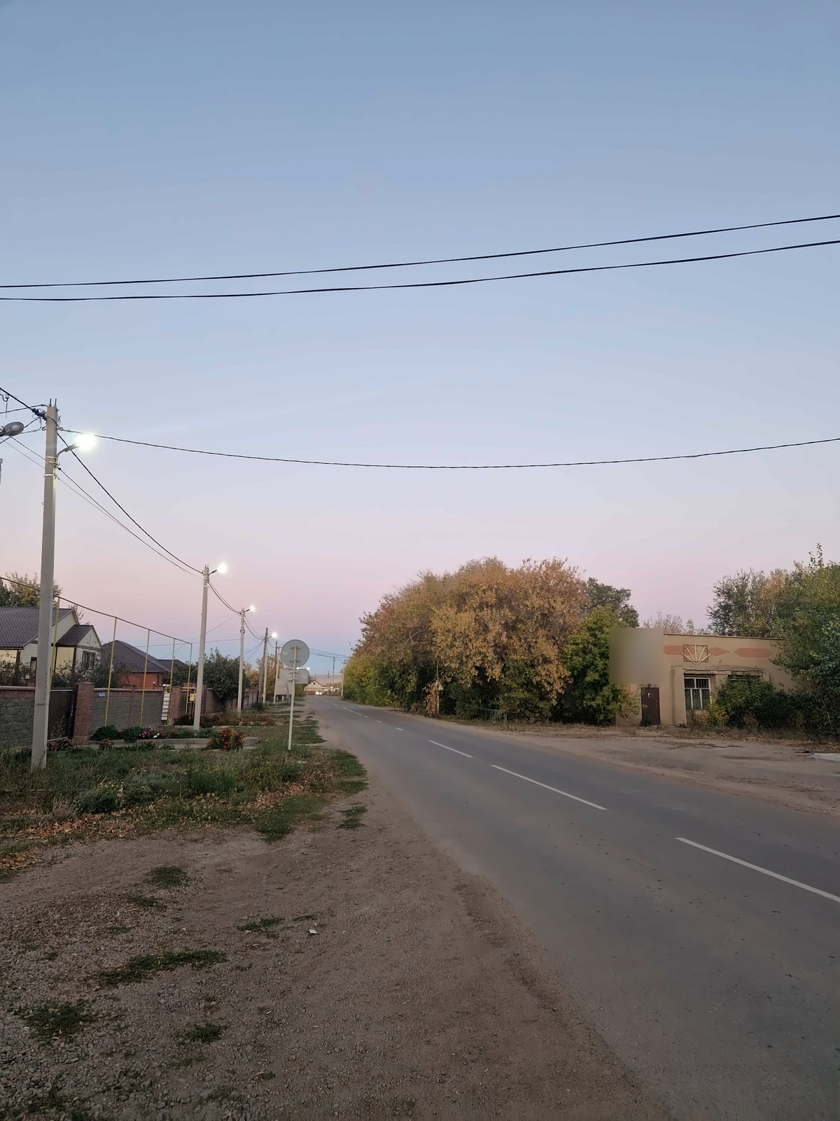 An empty street at dusk under a pink sky
