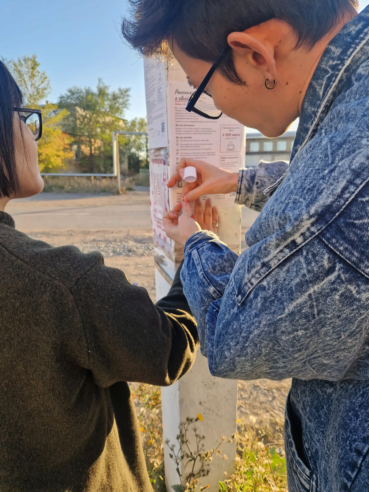 Two members of the team taping a poster to a pole
